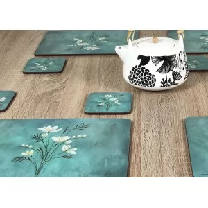 Wooden table with close up of teapot and Infinity, teal blue background, corkbacked floral placemats