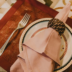 brown woven placemat with a round plate and decorative folded napkin